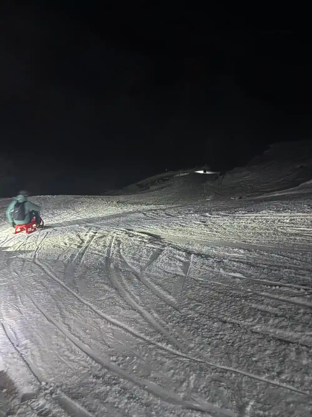 A lone sledder a long way down a floodlit track