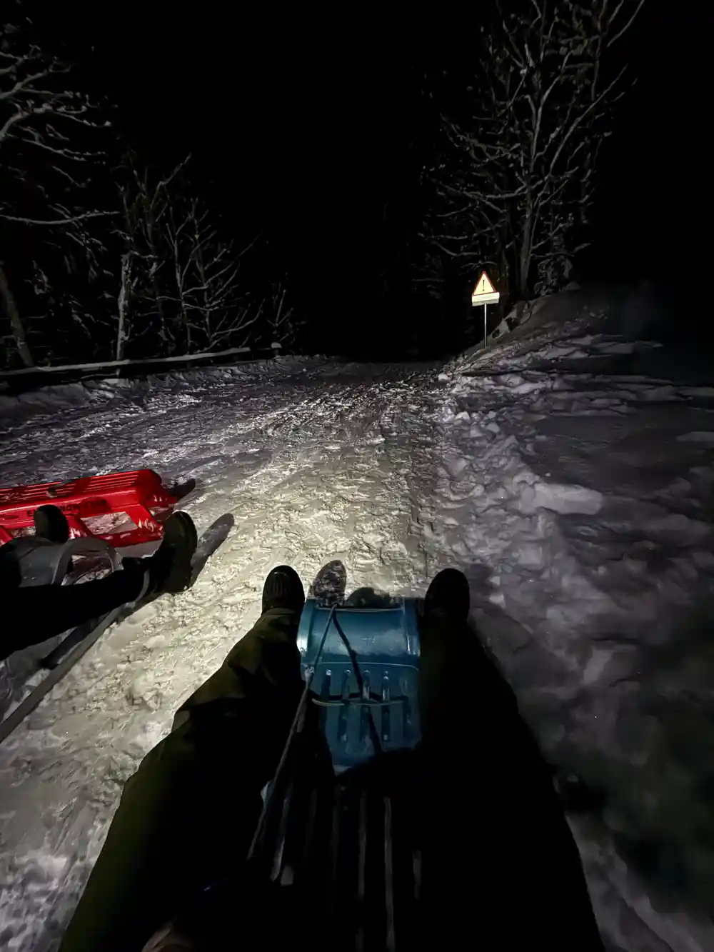 The rider's own view over boots and a blue sled on the track